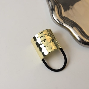 Close-up of golden hammered metal hair cuff with elastic band for minimalist styling