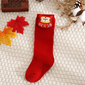 Close-up of red festive baby socks with cute cartoon tiger embroidery and knit texture