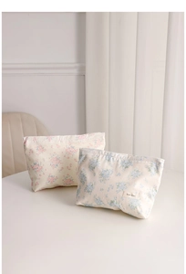 Detail of floral canvas cosmetic bags with H&R labels on a minimalist white table