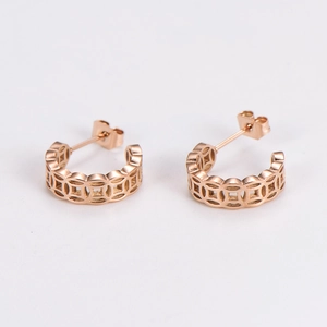 Close-up of rose gold cutout earrings featuring traditional Chinese ancient coin patterns