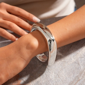Detailed view of polished silver irregular geometric cuff bracelet on a female wrist