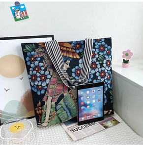 Detailed view of canvas tote bag with artistic floral pattern and striped handle strap