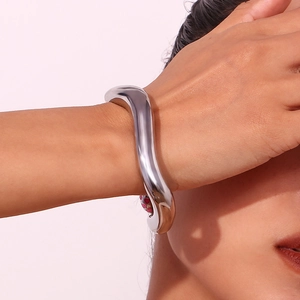 Close-up of silver irregular liquid wave bangle on a wrist with metallic luster