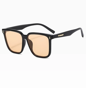 Detail of square black frame sunglasses with orange lenses and golden metal accents