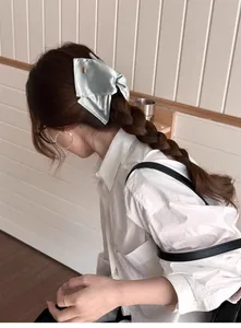 Détail d'une pince à cheveux avec nœud en satin bleu clair sur une coiffure élégante