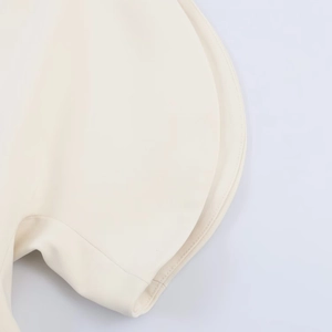 Detailed macro shot of fine stitching and curved layered hem on beige bubble sleeve top