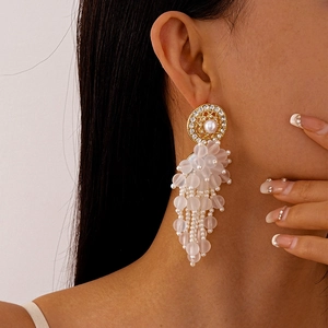 Gros plan de boucles d'oreilles élégantes à pampilles en perles sur un mannequin féminin
