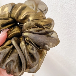 Detailed view of bronze metallic silk scrunchie showing glossy texture and pleats