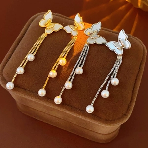 Detalle de pendientes de mariposa dorados y plateados con borlas de perlas finas