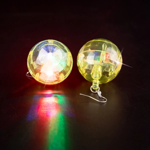 Close-up of glowing yellow disco ball earrings with colorful light reflections