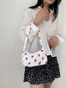 Detailed close-up of white nylon underarm bag featuring red strawberry print and zipper