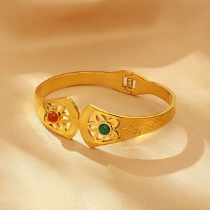 Detail showing vintage gold open bangle with red and green opal stones on silk