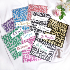 Close-up of colorful glitter letter stickers with positive phrases on white fabric