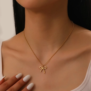 Collana a sfere placcata in oro con un ciondolo a fiocco minimalista indossata da una modella