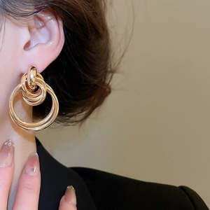 Close-up of golden multi-layered geometric hoop earrings on a model with black suit