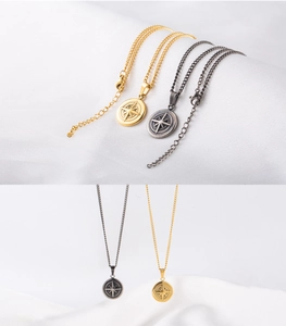Détails des colliers avec médaillons boussole or et argent sur fond de soie blanche
