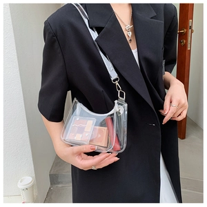 Close-up of transparent PVC underarm bag with silver chain and cosmetics inside