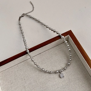 French style grey pearl necklace with a square pendant on a wooden jewelry display