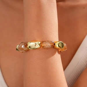 Macro view of bohemian amber resin beads and pebble-shaped gold metal chain on wrist