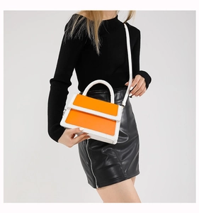 Bright orange crossbody bag styled with black sweater and leather skirt for a chic look