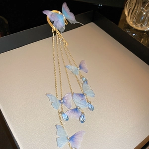 Détail d'un élégant clip d'oreille papillon doré avec pampilles en cristal bleu et perles