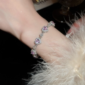 Close-up of pink heart-shaped gemstone bracelet with silver claw setting and diamonds