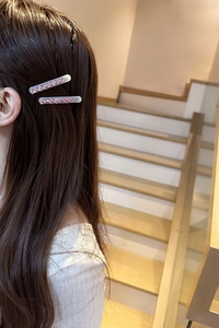 Close-up of model wearing stylish heart rhinestone hair clips with a pink glitter finish