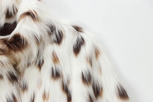 Detailed close-up of faux fur jacket collar showing soft white and brown spotted texture