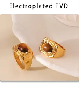 Macro detail of 18k gold-plated PVD tiger eye rings on a white ceramic display