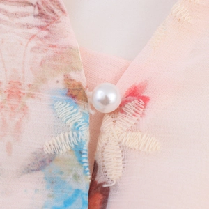 Robe en mousseline rose avec col à bouton perle et broderie blanche détaillée