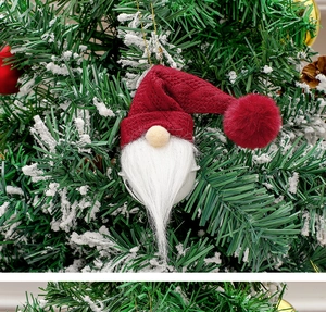 Close-up of a Christmas gnome bell with a red knit hat hanging on a snowy tree branch