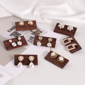Elegant pearl earring set displayed on a dark walnut wooden jewelry stand tray