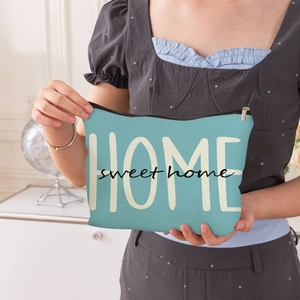 Trousse à maquillage bleue en toile avec imprimé Home Sweet Home tenue à la main