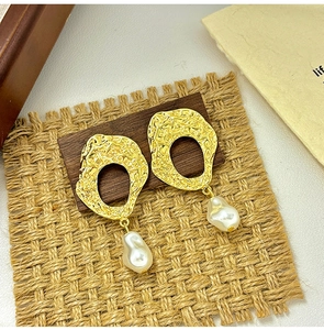 Close-up of baroque pearl drop earrings with hammered gold textured metal details