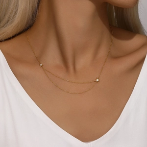 Detail of a double-layered gold S925 silver necklace with two sparkling star pendants