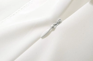 Close-up of high-quality invisible zipper on white textured fabric of a dress