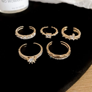 Macro shot of five gold-toned zircon rings on black velvet with luxury lighting