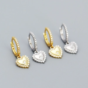 Detailed view of heart-shaped earrings featuring micro-paved cubic zirconia in gold and silver