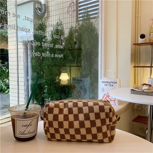Detailed knit texture of a brown and beige checkered makeup bag on a cafe table