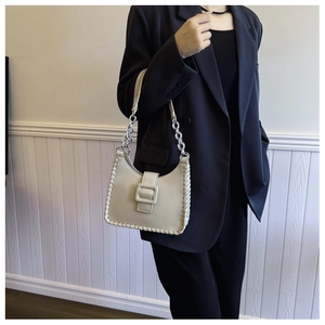Cream shoulder bag with woven edges and silver chain shown on a black suit model