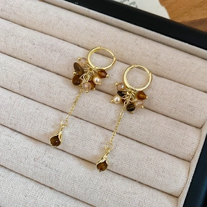 Detail von Vintage-Goldohrringen mit Tigeraugen-Perlen und langen Quasten in einer Box