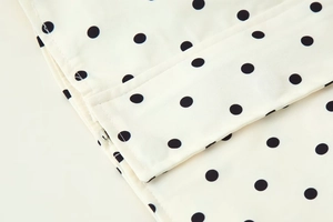 Close-up of white fabric with black polka dots and concealed zipper on the jacket