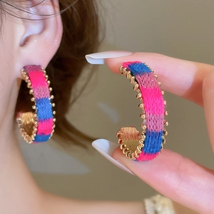 Detail of C-shaped hoop earrings featuring colorful knit texture and gold beaded edges