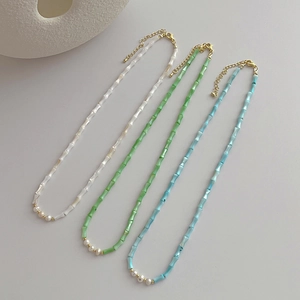 Detailed view of bamboo style necklaces with white pearls and colorful beads