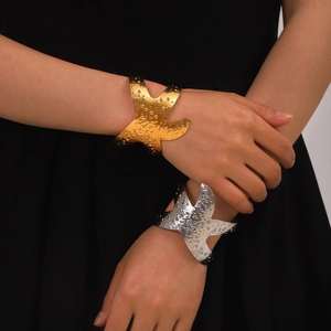 Detail of gold and silver starfish hammered cuff bracelets on a model's wrist