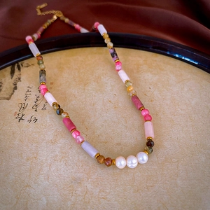 Detail of beaded necklace with natural stones and pearls on a calligraphy fan