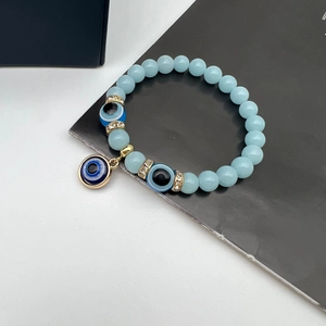 Macro detail of Turkish Evil Eye beaded bracelet with glowing light blue stones and gold charms