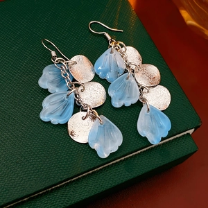 Détail de boucles d'oreilles en argent avec pendentifs coquillages bleus et glands