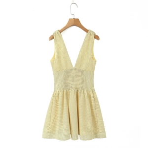 Detail of a bright yellow polka dot sleeveless dress with deep V-neck and slim waist