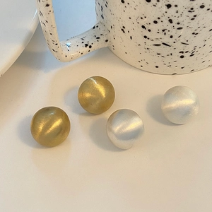 Minimalist matte brushed ball stud earrings in gold and silver finish on desk